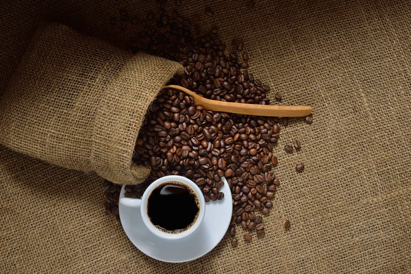 Vista dall'alto della tazza di caffè e chicchi di caffè su sfondo iuta — Foto Stock