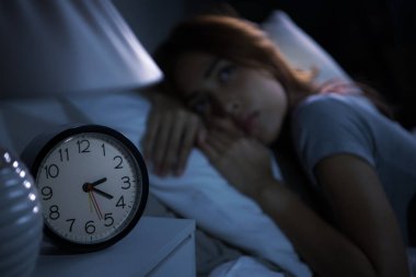 Depresyonda olan genç bir kadın uykusuzluktan uyuyamaz. Alarm saatine seçmeli odaklan