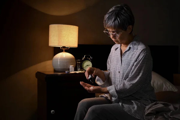 亚洲老年妇女在卧房吃药 — 图库照片