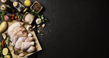 Çiğ tavuk butları ve siyah taş arka planda pişirecek malzemelerle birlikte tavuk budu.