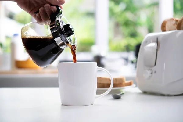 Een Hand Gieten Stomende Koffie Een Kopje Tafel Keuken — Stockfoto