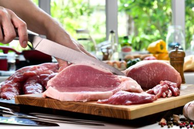 Mutfaktaki kesme tahtasının üzerinde taze çiğ domuz eti dilimliyorum.