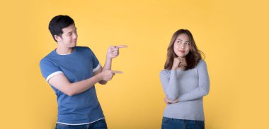 Mutlu Asyalı çift sarı arkaplan üzerindeki metin için boş kopya alanını işaret ediyor