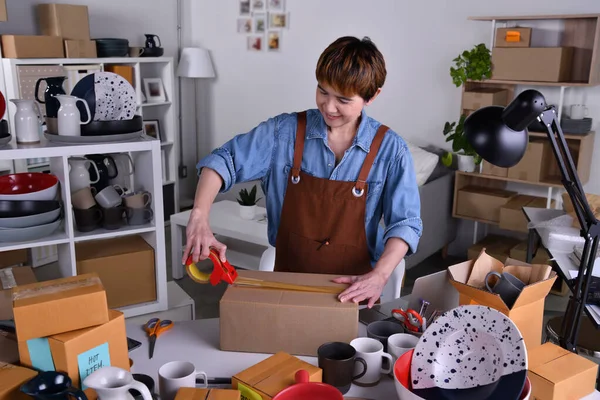 成熟的亚洲女企业家 业主将陶瓷产品包装成包装供交付和装运 网上销售在家工作的概念 — 图库照片