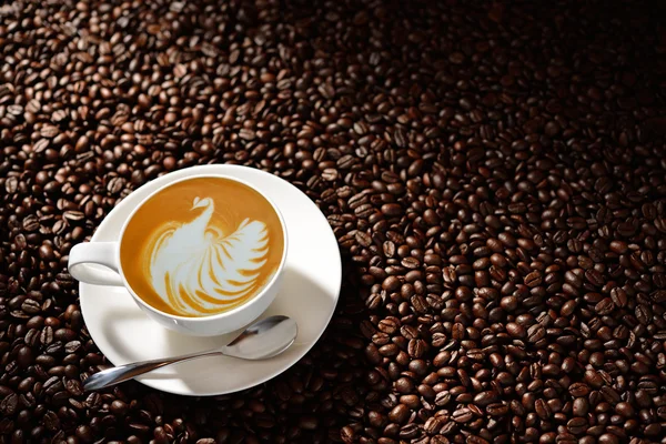 Cup of latte art, coffee and coffee beans — Stock Photo, Image