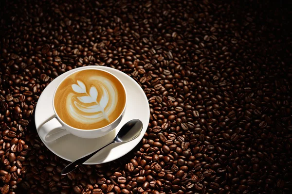 Cup of latte art, coffee and coffee beans — Stock Photo, Image