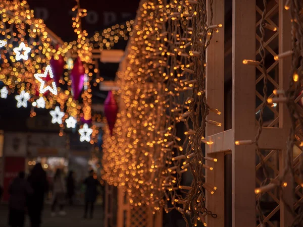 Christmas and New Year holidays decorations of streets with trees and shops with multicolored christmas string fairy lights glowing in the darkness outdoors. Winter holidays celbration concept.