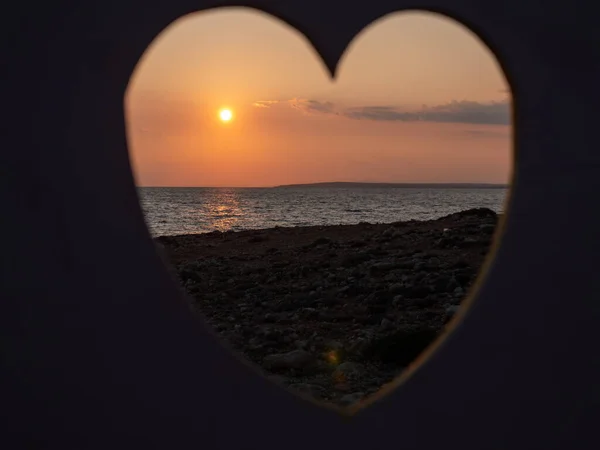 View through the hole in the shape of heart. People walking and making video at the seashore. Love, care and Valentine romantic  concept.