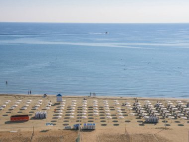 Güneşli manzaralı, güneşli, güneşli plaja bakan insanların güneşlendiği, yürüdüğü ve yüzdüğü, şemsiyeler, güneşlendiği, sakin mavi Akdeniz ve Kıbrıs Rum Kesimi 'ndeki bulutsuz gökyüzü..
