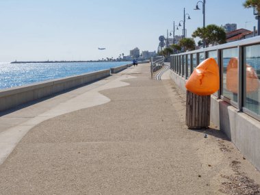 Uzun ve boş Piale Paşa, mavi Akdeniz boyunca, Larnaka havaalanına giden bir uçakla beton gezinti yapıyor. Çöp kutusundan çıkan turuncu plastik torba..