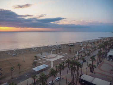 Finikoudes Palmiye Ağacı 'na tepeden bakan üst hava manzarası, sahildeki voleybol sahası ve Kıbrıs Rum Kesimi' nin Larnaka kentindeki Akdeniz 'deki yatlar. Suyun üzerinde güzel bir gökyüzü olan akşam manzarası.