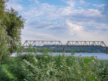 Köprünün üzerindeki Dinyeper Nehri 'nin sol kıyısından birçok yük vagonuyla birlikte uzun yük köprüsüne bakın. Kyiv şehir hayatı.