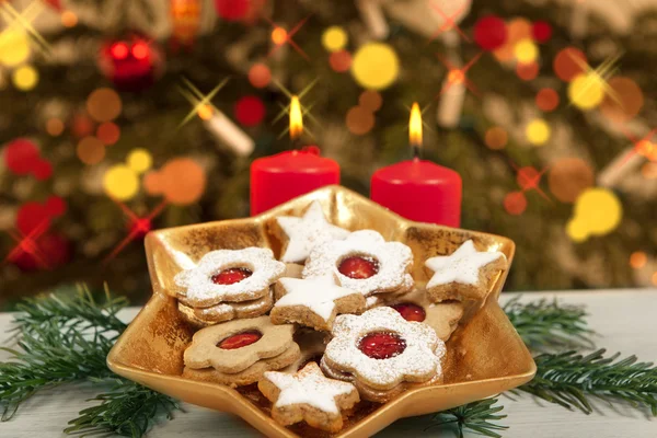 Koekjes en kaarsen onder kerstboom — Stockfoto