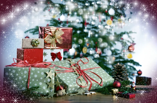 Christmas gifts in front of Christmas tree and stars — Stock Photo, Image