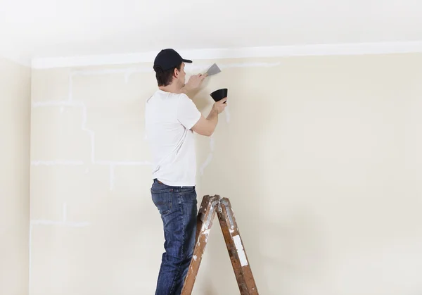 Man on ladder spackles wall — Stock Photo, Image