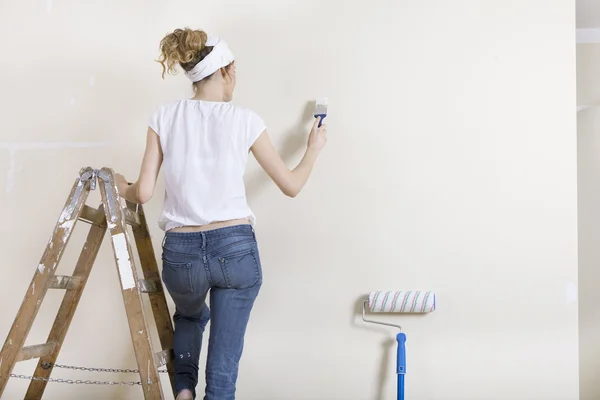 Une femme peignant mur sur échelle — Photo