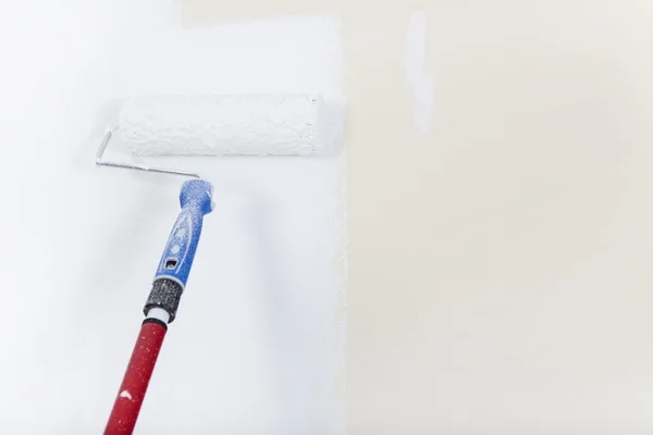 Paint roller on white wall — Stock Photo, Image