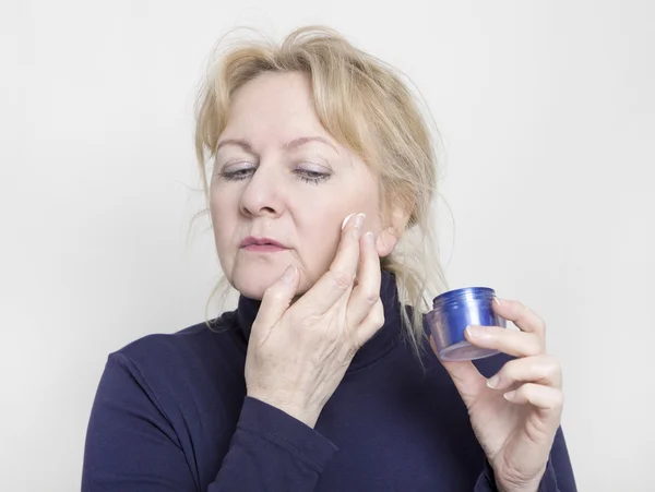 Elderly woman with face cream — Stock Photo, Image