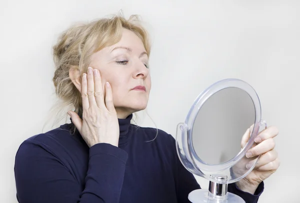 Older woman looking in mirror — Stock Photo, Image