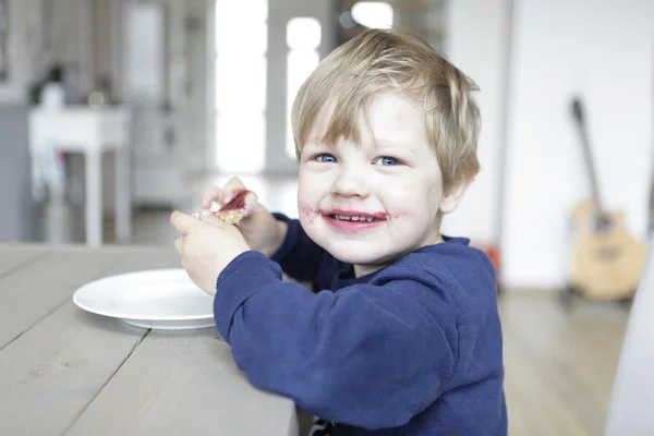 Blond boy eats jam — Stock Photo, Image