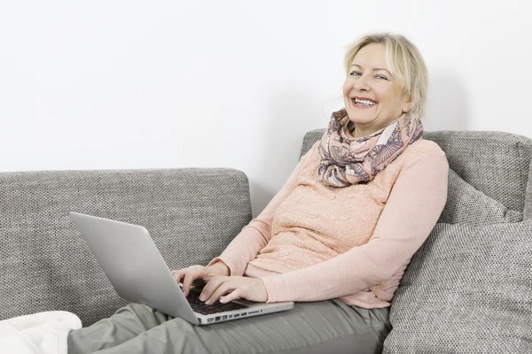 Frau mit Laptop auf Sofa — Stockfoto