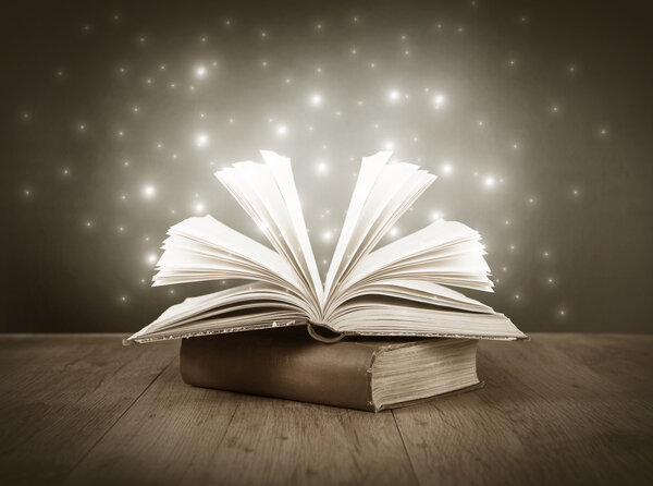 An old open book on a table in front of a blackboard