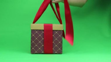 Hediye paketi kapanıyor. Kırmızı fiyonklu bir kutu. Kromakey.