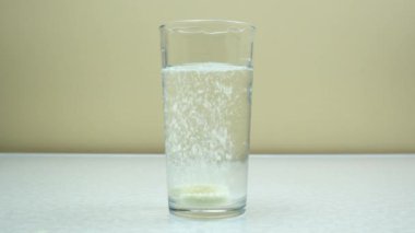 Açık arkaplanda şeffaf bir camda karbonatlı renkli su. Uzayı kopyala Mesajın için yer aç. Yakın plan..