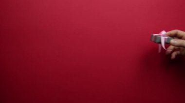 Erkek eli kırmızı arka planda bir kadına hediye verir..