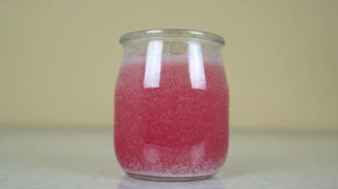 Açık arkaplanda şeffaf bir kavanozda karbonatlı renkli su..