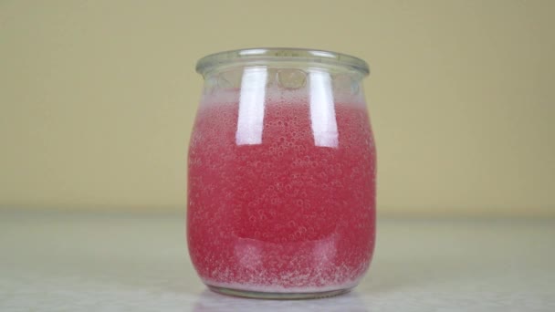 Carbonated colored water in a transparent jar on a light background. — Stock Video