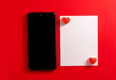 Mesajı iletmek için boş kartı olan akıllı bir telefon. Sevgililer Günü arkaplanı. 