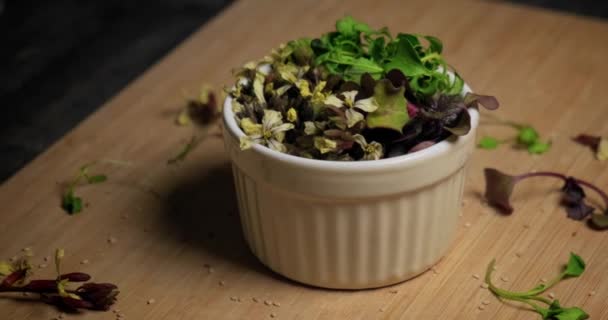 Primer plano de microgreens orgánicos frescos y flores comestibles en un tazón. — Vídeos de Stock