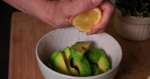 Squeezing lemon juice on fresh sliced avocado in a bowl. — стоковое видео