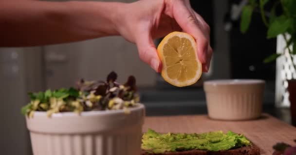 Zitronensaft von Hand auf Avocadoaufstrich auf Brot pressen, gesundes Ernährungskonzept. — Stockvideo