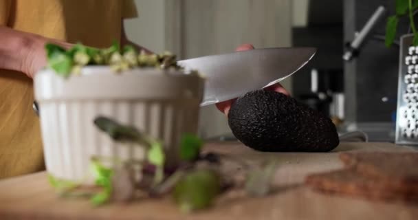 Woman slicing fresh ready-to -eat avocado to make sandwich with microgreens. — стоковое видео
