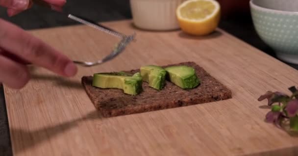 Close up espalhando abacate maduro fresco no pão orgânico, conceito de alimentação saudável. — Vídeo de Stock