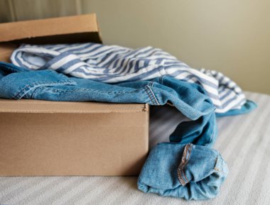 İçinde ikinci el kıyafetler olan karton bir kutu. Sürdürülebilir moda, kullanılmış giysileri yeniden satma