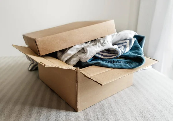 Cardboard box with pre owned clothes inside. Sustainable fashion, resale used clothes