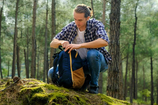 Young active man with backpack at forest during sunny day. Local travel concept