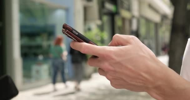 Uomo digitando smartphone a occupato strada della città. — Video Stock