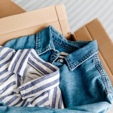 İçinde giysiler olan kart kutusundan genel manzara. Sürdürülebilir moda, kullanılmış giysileri yeniden satma