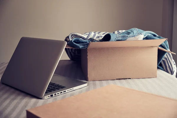 Карточная Коробка Одеждой Открытым Ноутбуком Кровати Продать Одежду Концепции — стоковое фото