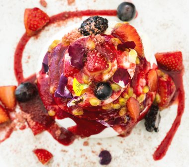 Taze böğürtlenli gurme Pavlova pastası ve krem şanti katmanları bir tabakta servis ediliyor, mükemmel yaz tatlısı.