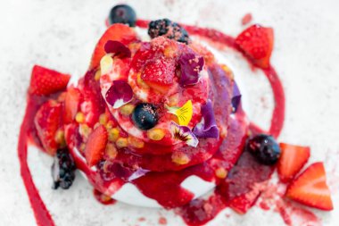 Taze böğürtlenli gurme Pavlova pastası ve krem şanti katmanları bir tabakta servis ediliyor, mükemmel yaz tatlısı.