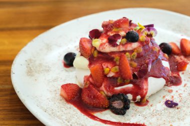 Taze böğürtlenli gurme Pavlova pastası ve krem şanti katmanları bir tabakta servis ediliyor, mükemmel yaz tatlısı.