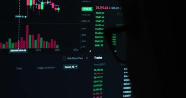 Yeşil ve kırmızı göstergeli kripto fiyatlarını canlı güncelleyen monitör, bitcoin 'in finansal tabloları, online yatırım platformu, gözlüklü kişi önde.