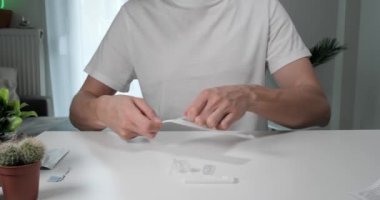 Coronavirus için hızlı bir test yapmak için burun temizleme çubuğuyla paket açan adam, Covid-19 antijen testi..