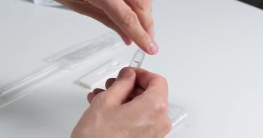 Geniz temizleme çubuğuyla hızlı antijen testi yapmak, tampon kesesinden tüpe sıvı dökmek, ellerini kapat..