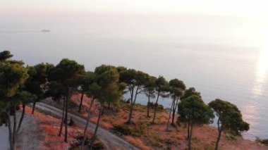 Gün batımında turkuaz deniz kenarındaki yüksek uçurum manzarası.